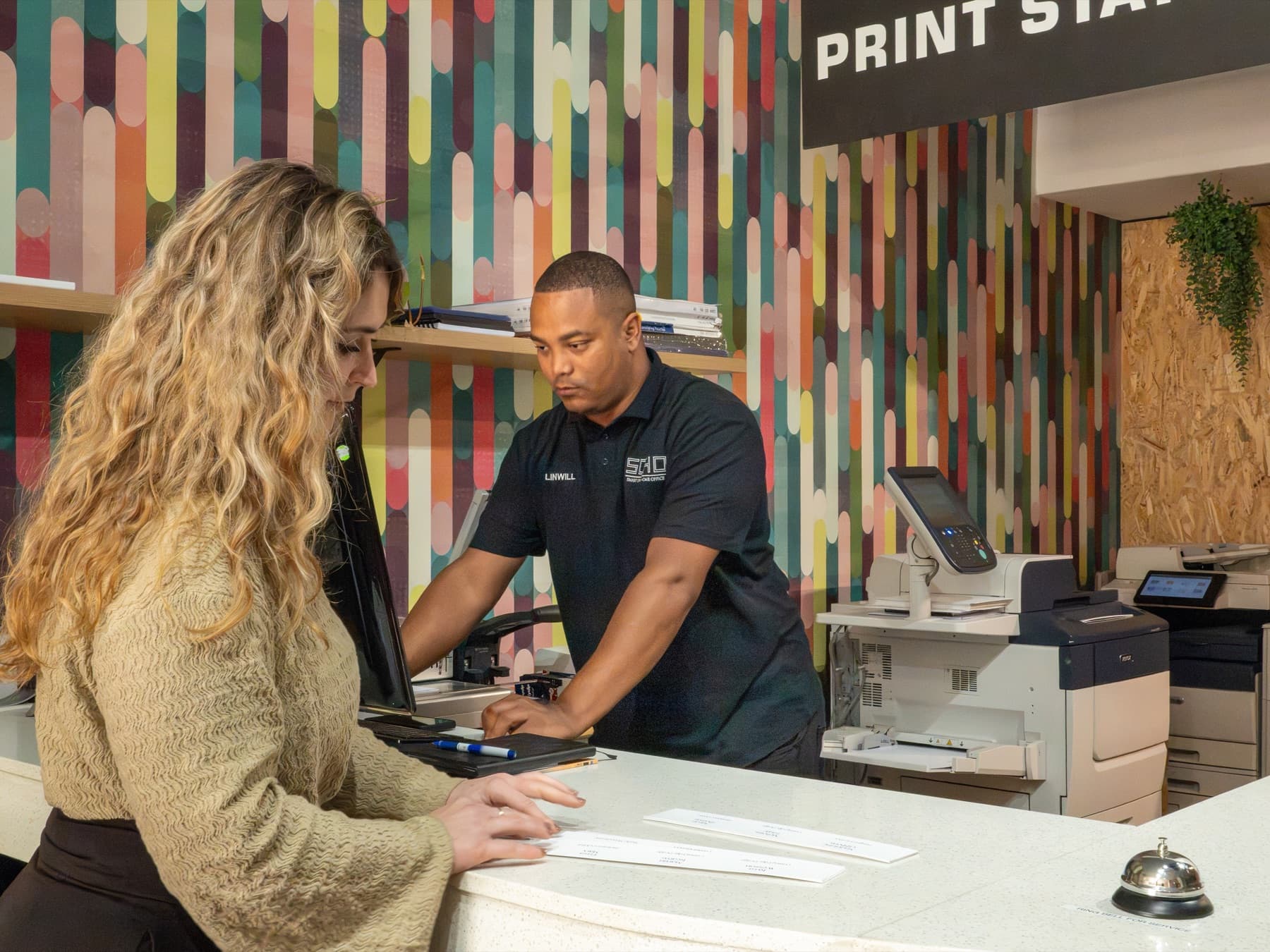 A SOHO staff member going through a print job with a customer at the print station counter.