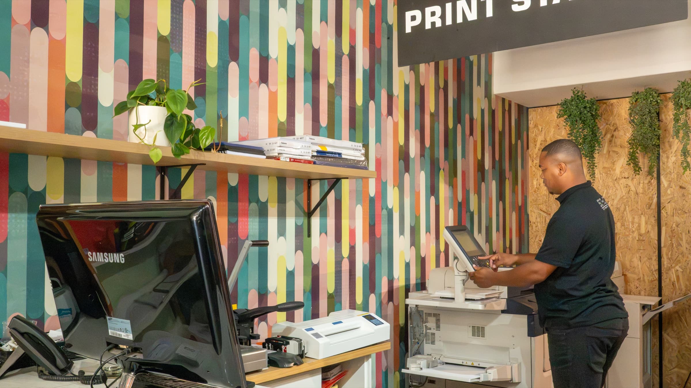 The SOHO print station — production printers and finishing equipment beneath the Print Station sign.