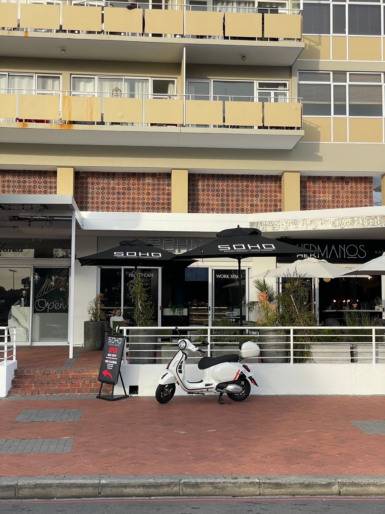 The SOHO shopfront on Main Road, Green Point, with branded umbrellas over the pavement seating.